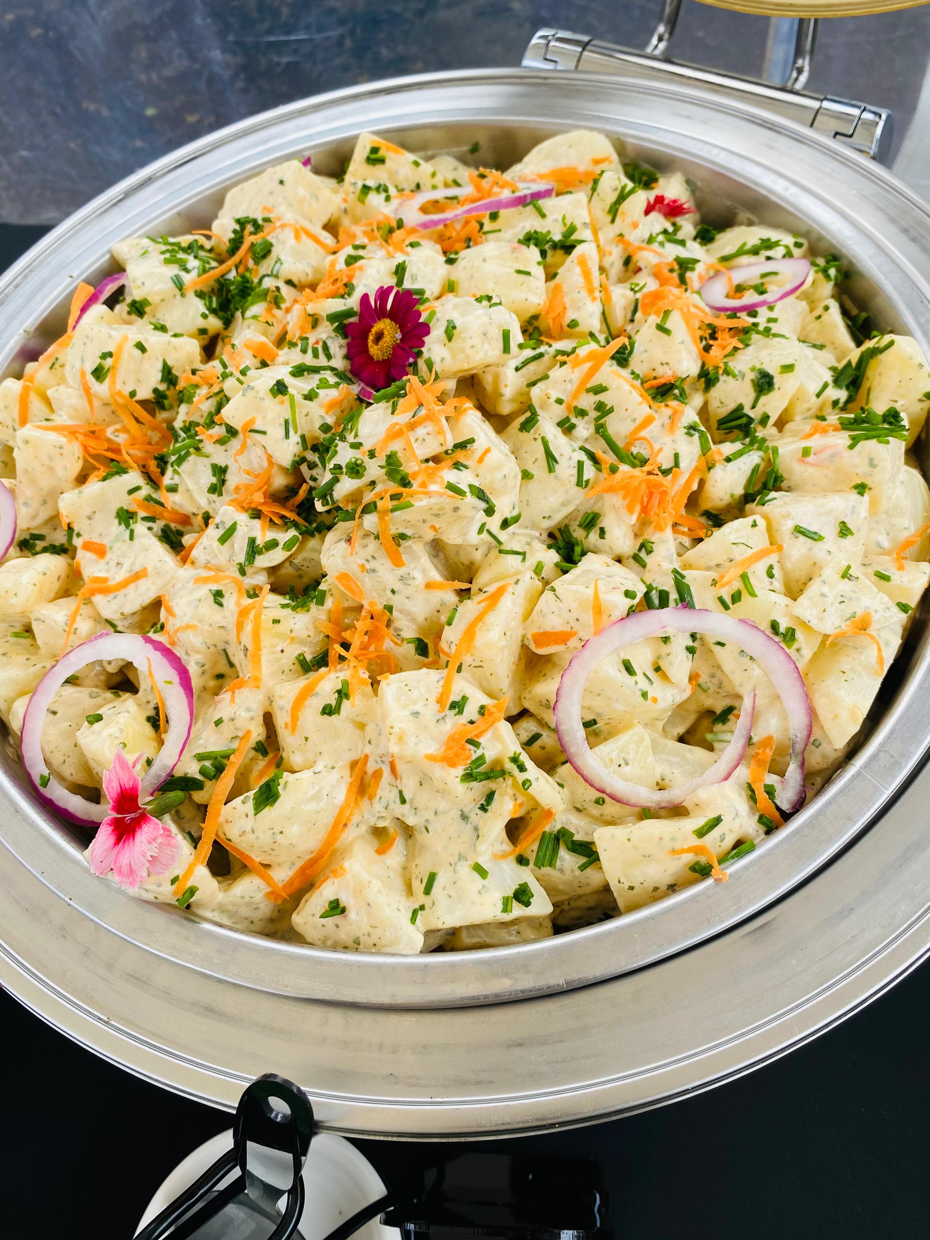 Potato salad garnished with chives, carrot, and edible flowers