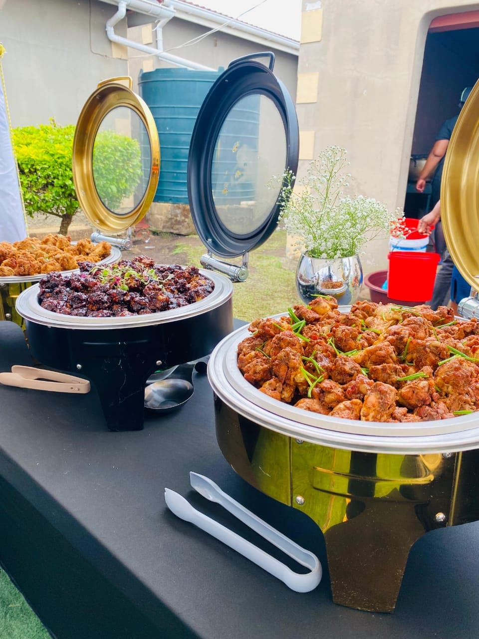 Chafing dishes of catered chicken dishes at an outdoor venue
